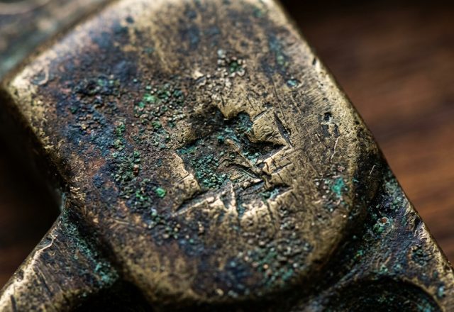 Close up of an antique brass patina with green verdigris oxidation on vintage metal hardware.