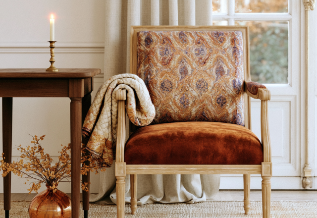 Vintage accent chair with patterned upholstery and rust velvet cushion next to a wooden side table