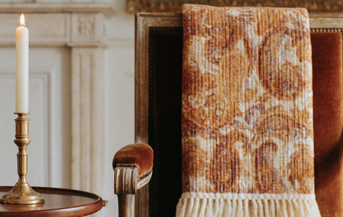 Vintage armchair styling with a patterned throw blanket and a brass candlestick on a side table.