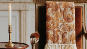 Vintage armchair styling with a patterned throw blanket and a brass candlestick on a side table.
