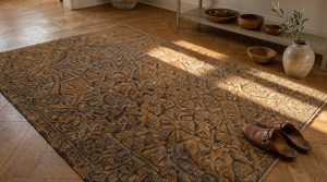 A distressed vintage wool area rug placed on herringbone hardwood flooring in a warm living room.