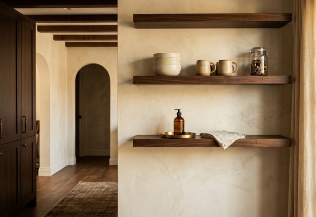 warm minimalist shelving on textured plaster wall with ceramic mugs and dark wood cabinets