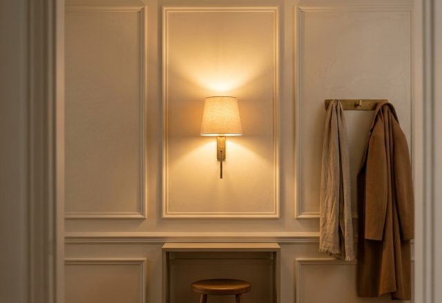 A warm entryway featuring classic wall sconce lighting, wall molding, and a brass coat hook.
