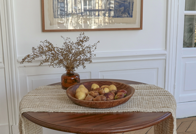 Wooden dining table decor featuring a neutral linen runner and a wooden bowl filled with pears and figs.